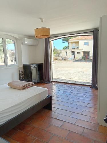 ein Schlafzimmer mit einem Bett und einem großen Fenster in der Unterkunft Villa Les Grenadines RDC in Mèze