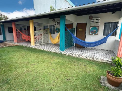 a house with hammocks on the front of it at Pousada Canto dos Artistas in Porto De Galinhas