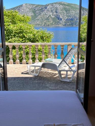 a white chair on a balcony with a view of the water at Beachfront Apartment Mery, Kneže in Račišće