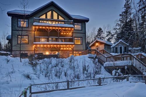 a house with lights on it in the snow at Front RIVER private BEACH 2 HOT TUBS 15 p SAUNA in Labelle