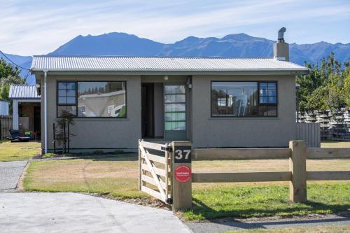 a small house with a fence in front of it at The Crib Haven - Te Anau Holiday Home in Te Anau