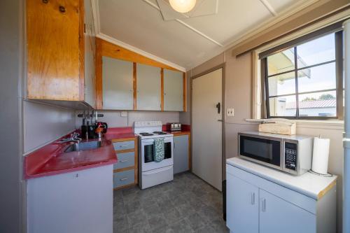a kitchen with a sink and a microwave at The Crib Haven - Te Anau Holiday Home in Te Anau