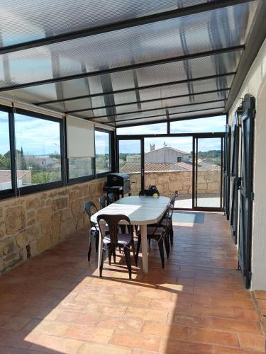 une salle à manger avec une table, des chaises et des fenêtres dans l'établissement Villa Les Grenadines ETAGE, à Mèze
