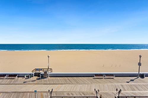 a sandy beach with benches and the ocean at Americana Motor Inn on Boardwalk in Ocean City