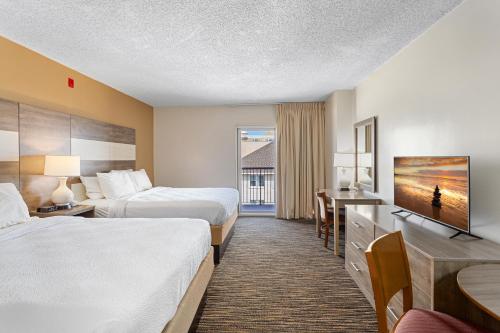 a hotel room with two beds and a flat screen tv at Americana Motor Inn on Boardwalk in Ocean City