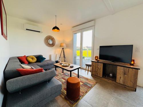 a living room with a couch and a flat screen tv at jolie chalet Normand - classée 3 étoiles in Beuzeville