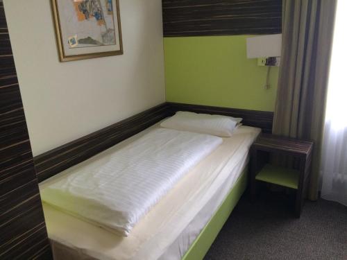 a small bed in a room with green walls at Behringers City Hotel Nürnberg in Nuremberg