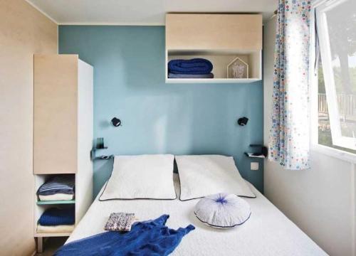 une chambre avec un lit avec un mur bleu dans l'établissement Camping - Parc aquatique - ccaggcd, à Olonne-sur-Mer