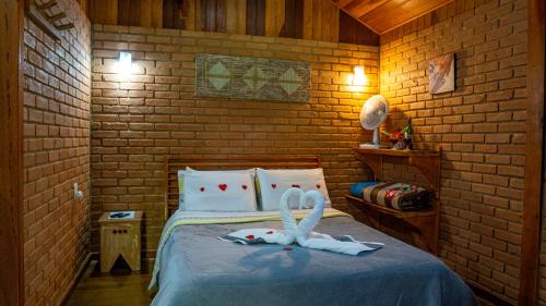 a bedroom with a bed with two swans on it at Chalés Das Estrelas in Visconde De Maua