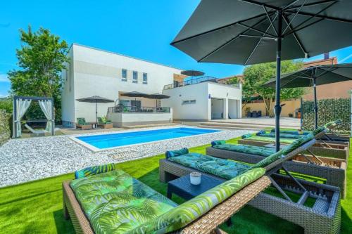 a pool with chairs and umbrellas in a backyard at Villa Nikoma in Dicmo