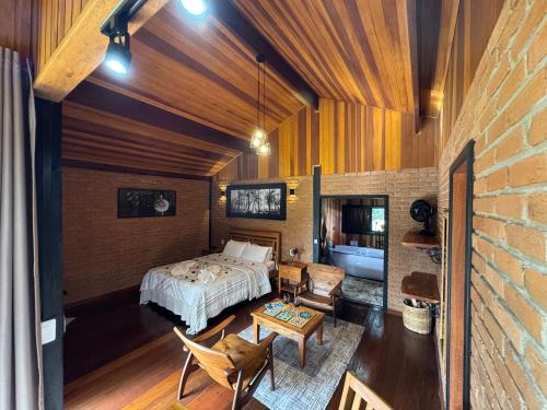 a bedroom with a bed and a couch and a table at Chalés Das Estrelas in Visconde De Maua