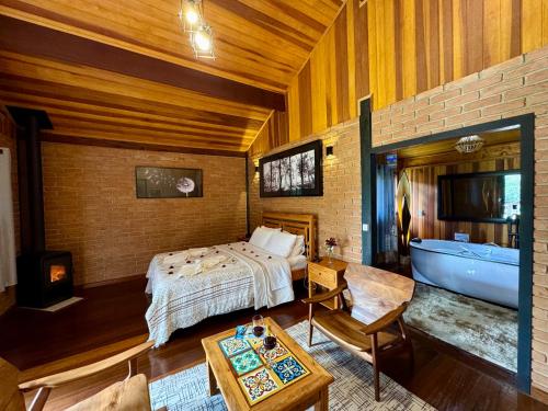 a bedroom with a bed and a tub in a room at Chalés Das Estrelas in Visconde De Maua
