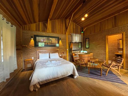 a bedroom with a bed and a table and chairs at Chalés Das Estrelas in Visconde De Maua