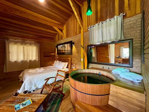 a bedroom with a bed and a tub in a room at Chalés Das Estrelas in Visconde De Maua