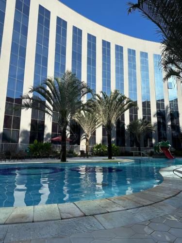 a swimming pool in front of a building with palm trees at Barretos Park Hotel, Parque do Peão de Barretos in Barretos