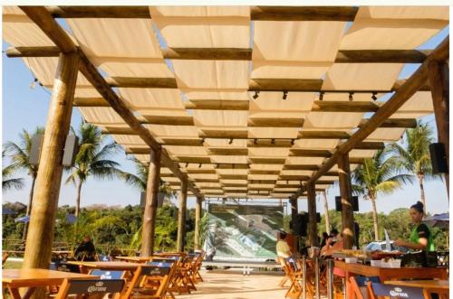a restaurant with wooden tables and chairs and palm trees at Barretos Park Hotel, Parque do Peão de Barretos in Barretos