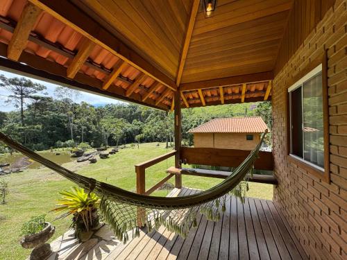 a hammock on a porch of a house at Chalés Das Estrelas in Visconde De Maua