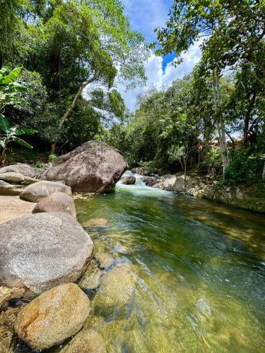 a river with rocks and trees on the side at Chalés Das Estrelas in Visconde De Maua