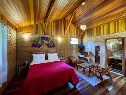 a bedroom with a large bed with a red blanket at Chalés Das Estrelas in Visconde De Maua