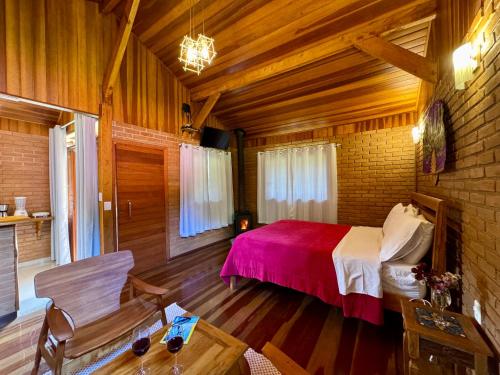 a bedroom with a bed and a table in a room at Chalés Das Estrelas in Visconde De Maua