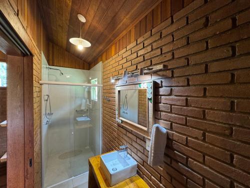 a brick walled bathroom with a sink and a shower at Chalés Das Estrelas in Visconde De Maua