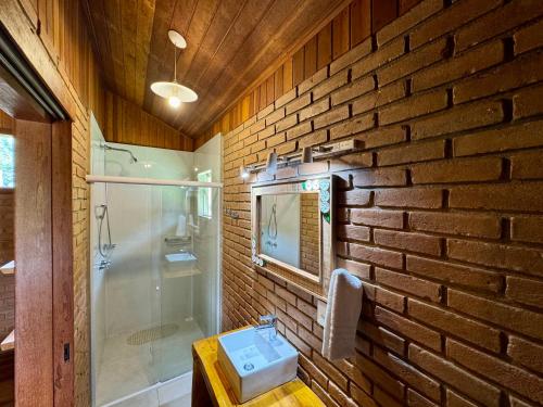 a brick walled bathroom with a sink and a shower at Chalés Das Estrelas in Visconde De Maua