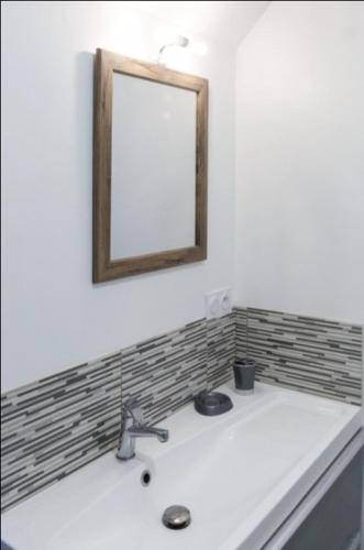 La salle de bains est pourvue d'un lavabo et d'un miroir mural. dans l'établissement App 3étoiles Tout Confort Neuf Vue Mer avec Jardin CAROUAL, à Erquy