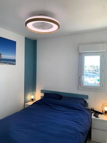 une chambre avec un lit bleu et une fenêtre dans l'établissement Résidence Port Soleil Bâtiment B1 - Appartement T2 - Résidence Port Soleil MAE-1271, au Cap d'Agde