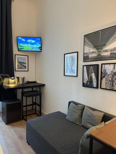 a bedroom with a bed and a desk with a tv on the wall at urban-studios-cologne I studio in Cologne