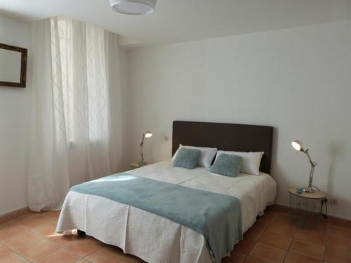 a bedroom with a large bed with two blue pillows at Le jardin de Saint Just in Narbonne