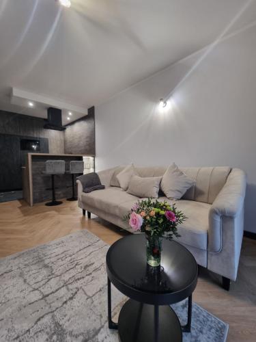 a living room with a couch and a table with flowers at Parkowa Premium Apartment in Gdynia