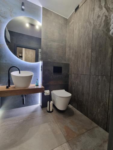 a bathroom with a sink and a toilet and a mirror at Parkowa Premium Apartment in Gdynia