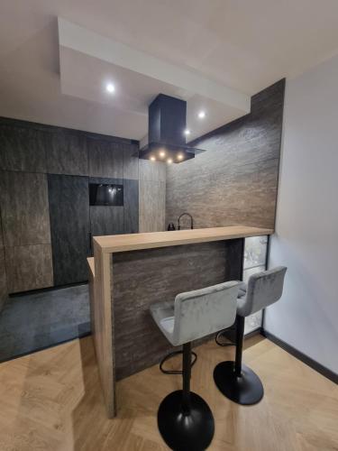 a kitchen with a counter and a bar with two chairs at Parkowa Premium Apartment in Gdynia