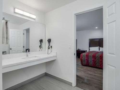 a bathroom with a sink and a mirror and a bed at Alameda Motel San Jose in San Jose