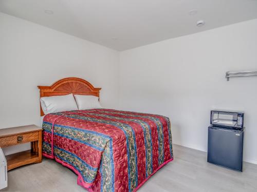 a bedroom with a bed and a small refrigerator at Alameda Motel San Jose in San Jose