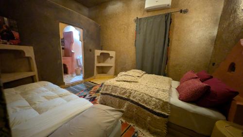 a bedroom with two beds in a room with a window at Riad Amar in Merzouga