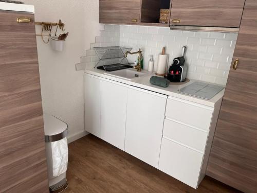 une cuisine blanche avec un évier et un comptoir dans l'établissement Appartement vue sur les Pyrénées 4pers aux pieds des pistes, à Ax-les-Thermes