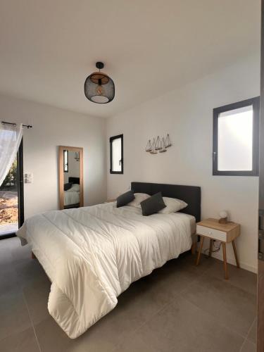 un grand lit blanc dans une chambre avec une fenêtre dans l'établissement Villa neuve, piscine chauffée, à Zonza