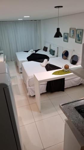 a hotel room with three beds and a table at Laguna Beach Flat GV in Porto De Galinhas