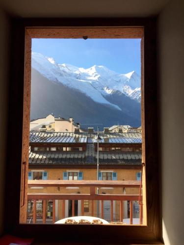 une fenêtre avec vue sur un bâtiment avec des montagnes enneigées dans l'établissement Chamonix Bellevue, à Chamonix-Mont-Blanc