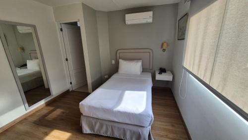 a small bedroom with a white bed and a mirror at El Golf Hotel Boutique in Lima