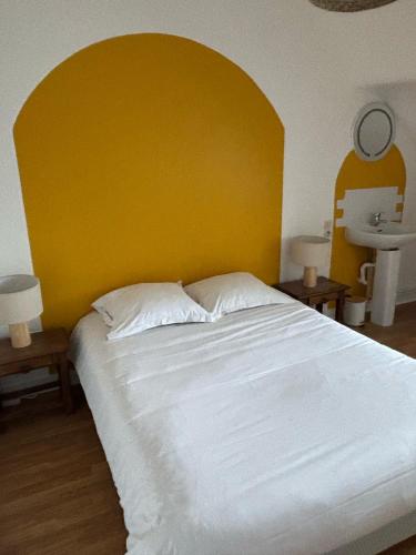 a bedroom with a large white bed with a yellow headboard at Le Manoir de Conteville in Paluel