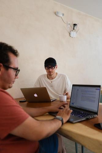 two men sitting at a table with their laptops at SUUT Hostal Boutique in Playa del Carmen