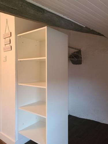 a closet with white shelves in a room at Le clos des vignes in Sarcey