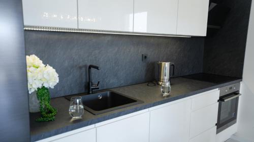 a kitchen counter with a sink and flowers in a vase at Crystal Adria in Privlaka