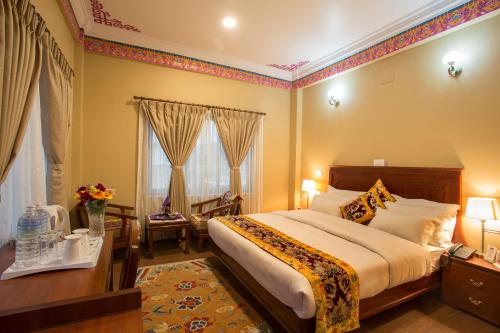 a hotel room with a bed and a desk and windows at Hotel Harmika in Kathmandu