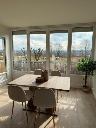 une salle à manger avec une table, des chaises et des fenêtres dans l'établissement Le Cocon, à Beauvais