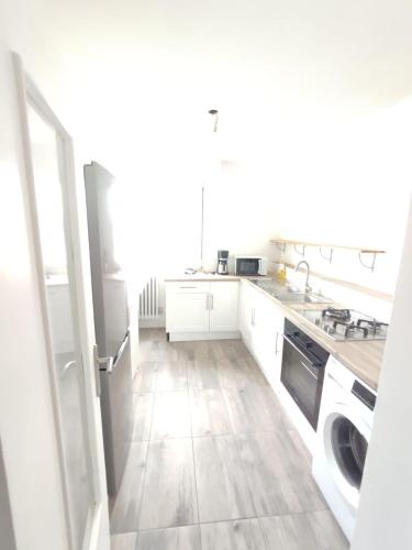 une cuisine avec des armoires blanches et un plancher en bois dans l'établissement Appartement 3 chambres, à Brest