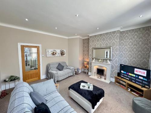 a living room with a couch and a television at Park View Maisonette, Luxurious 3 bed holiday home in Whitley Bay
