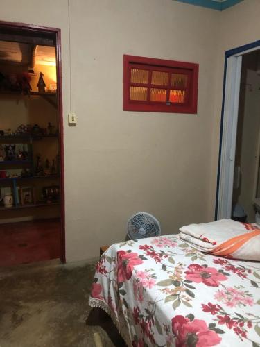 a bedroom with a bed with a flowered blanket at Pousada e Hostel Cantinho dos Chalés in São Luiz do Paraitinga